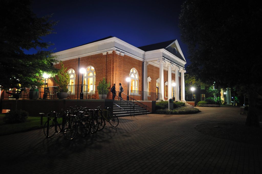 Hege Library building at night. It is lit up by streetlamps and has a dark blue sky behind it.