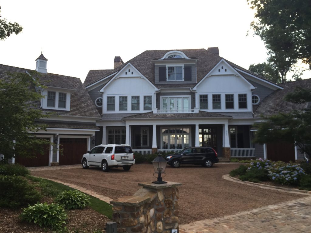 A picture of a really big fancy house with cars in a drive way in front